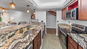 Una cocina moderna con encimeras de granito, electrodomésticos de acero inoxidable y armarios de madera.