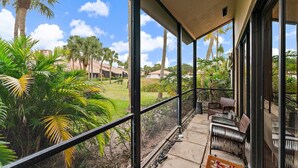 Un espacio al aire libre cubierto con vistas a un jardín y palmeras.