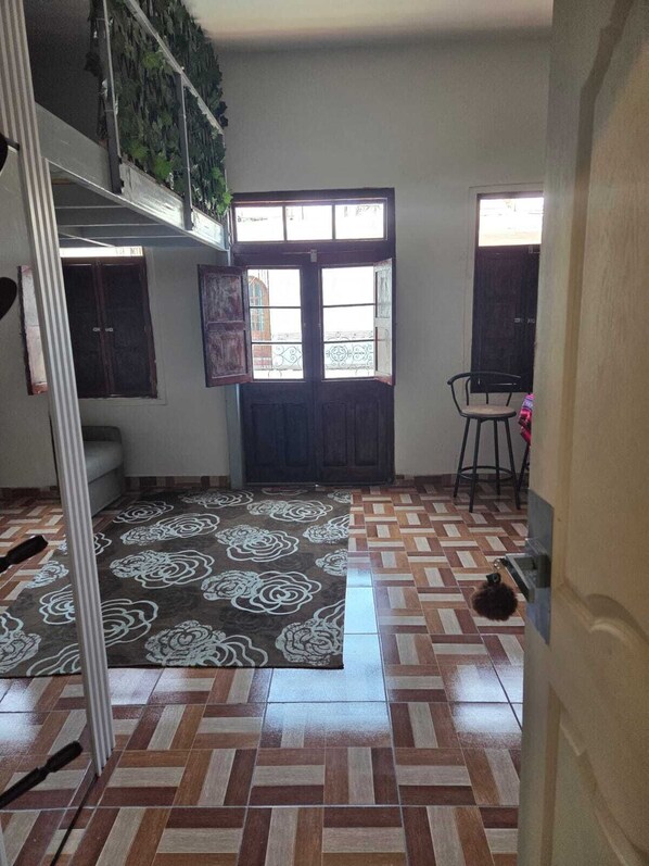 A room with a patterned floor, a large window with a view, and a chair. - In the historical center and with all services nearby. (Arequipa)