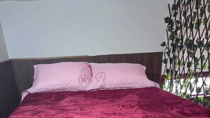 A bed with a deep red velvet bedspread and matching pillows, a wooden floor, and a wall with a vertical garden. - In the historical center and with all services nearby. (Arequipa)