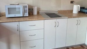 A kitchen with a microwave, a gas stove, cabinets, and a patterned floor. - In the historical center and with all services nearby. (Arequipa)