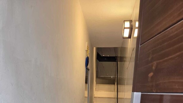 A narrow hallway with a staircase leading to an upper floor. The walls are plain, and there is a wooden door on the right. - In the historical center and with all services nearby. (Arequipa)