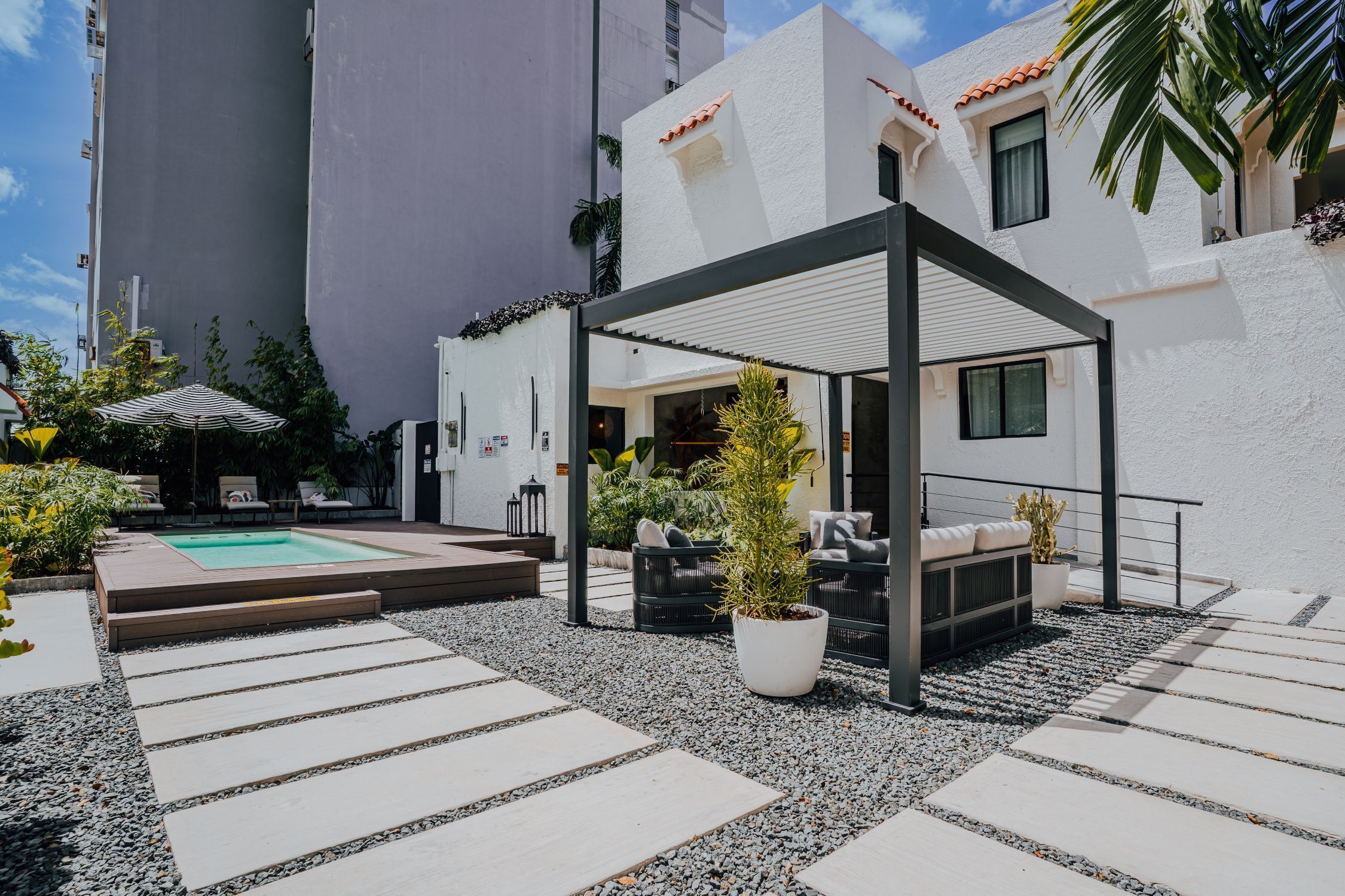 Un patio moderno al aire libre con piscina, zona de estar y plantas en macetas.
