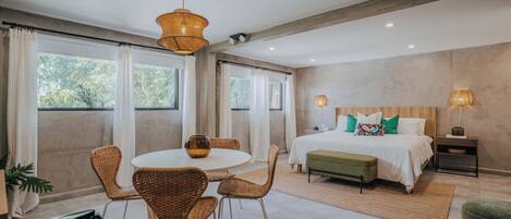 A modern bedroom with a large bed, a dining table with chairs, and a piano.