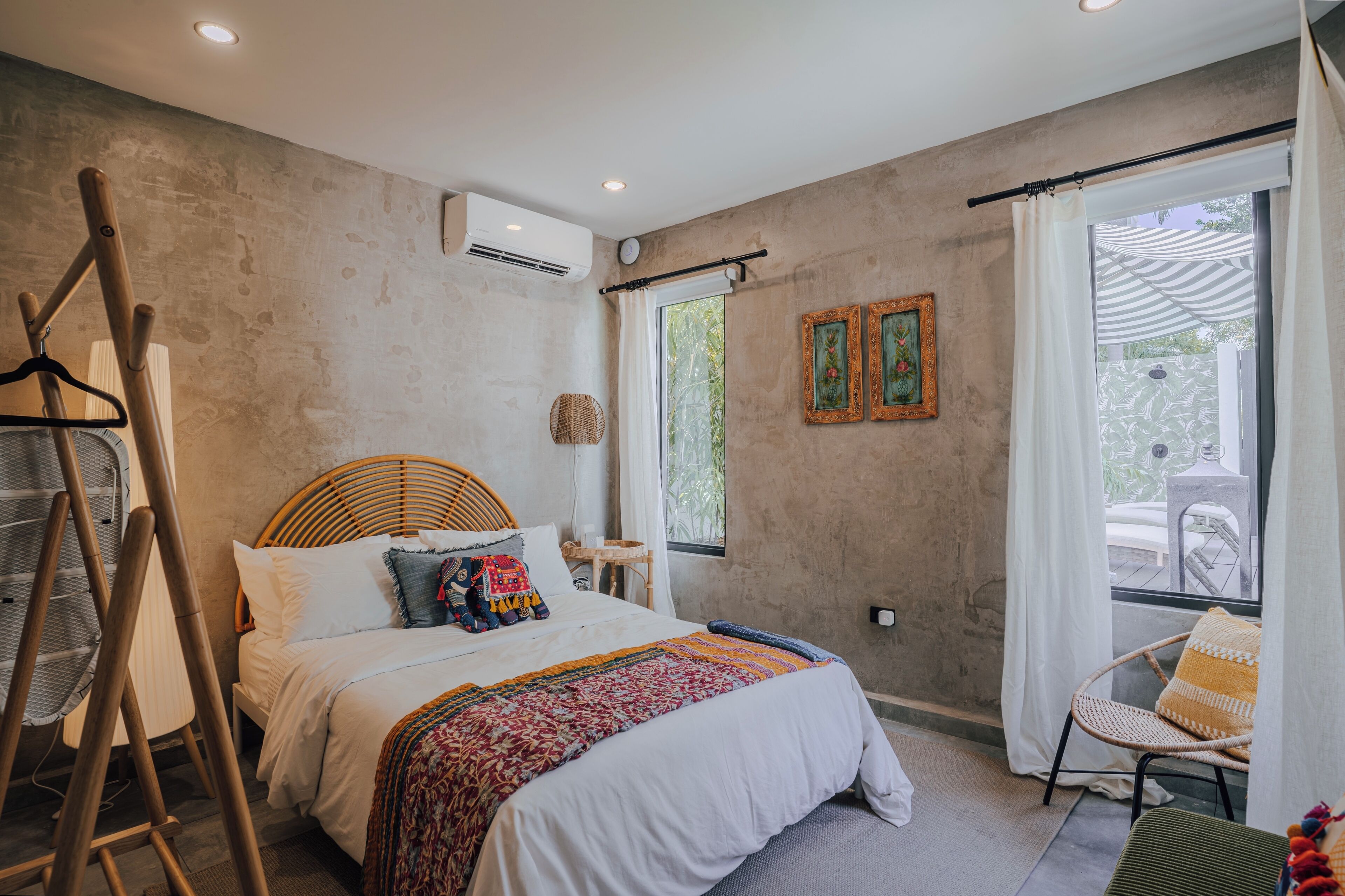 A bedroom with a bed, a chair, a hanging chair, and a window with curtains.