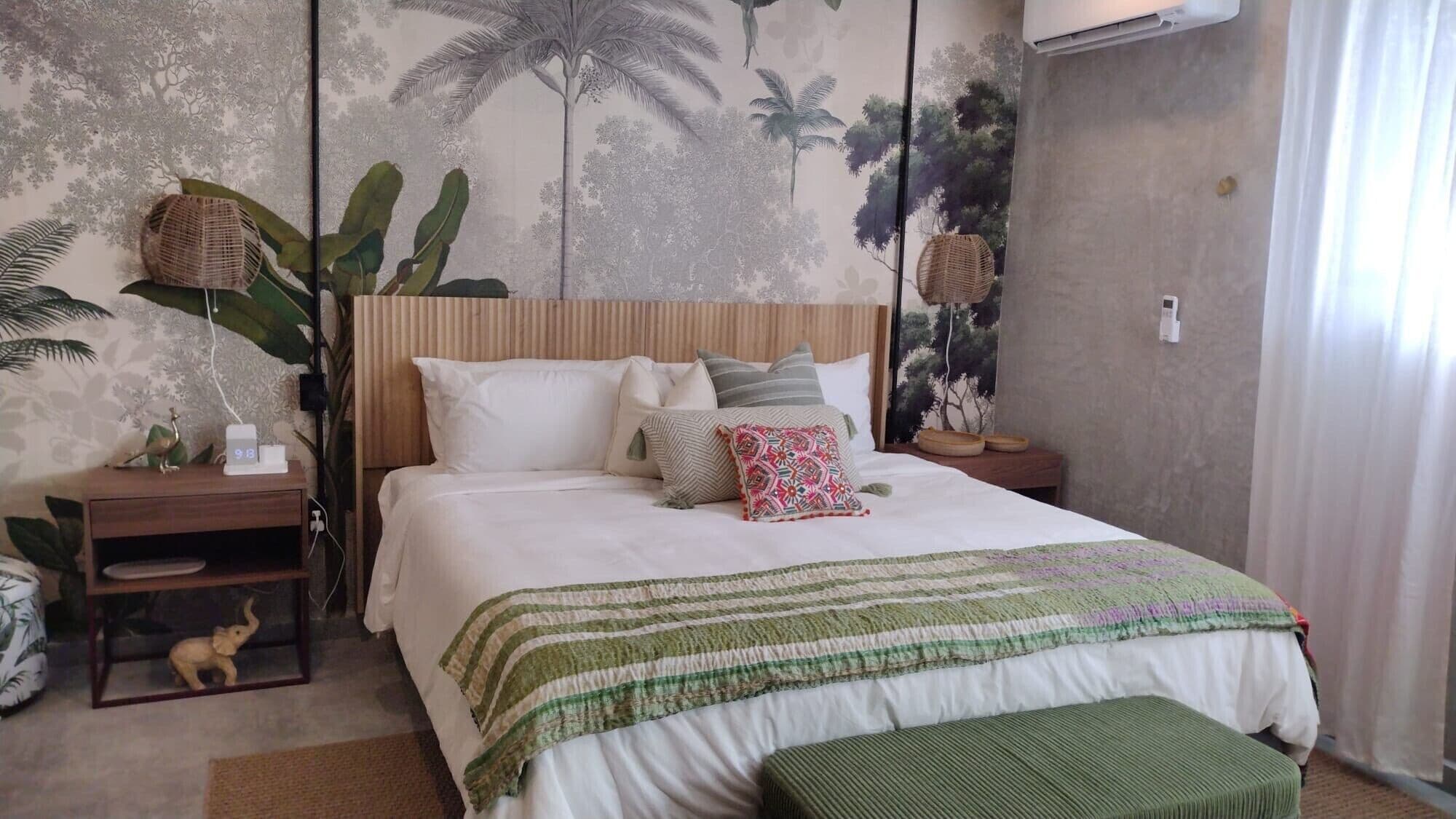 A bedroom with a bed, nightstands, a wall mural, and a window with curtains.