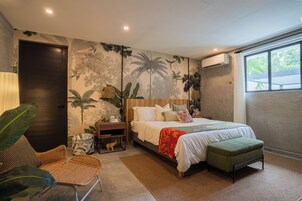 A bedroom with a bed, a nightstand, a chair, and a large window.