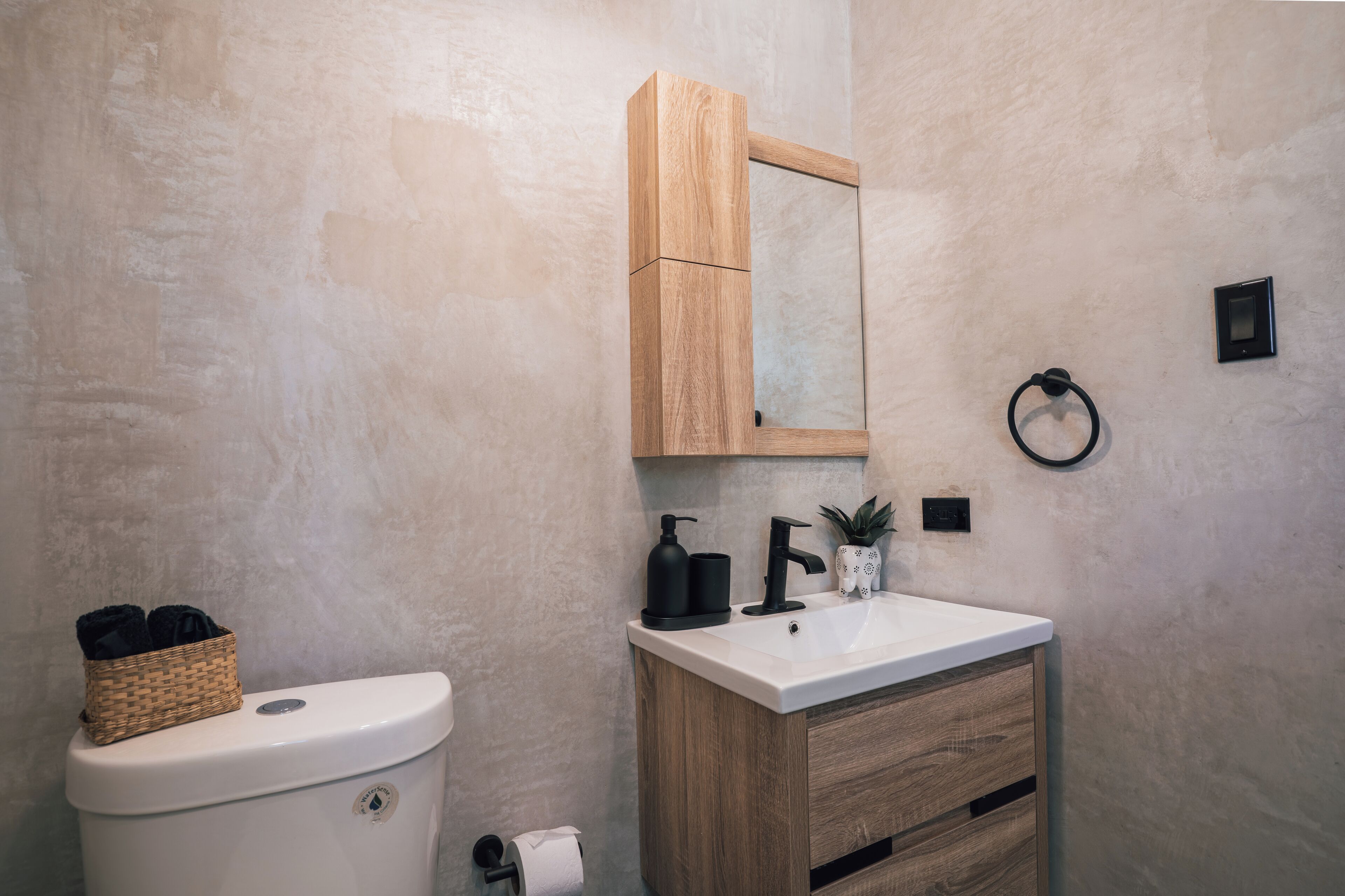 A bathroom with a wooden cabinet, a white sink, and a toilet.