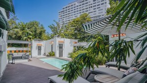 A poolside area with lounge chairs, a small pool, and a pergola with striped awning. - Flor De India (San Juan)
