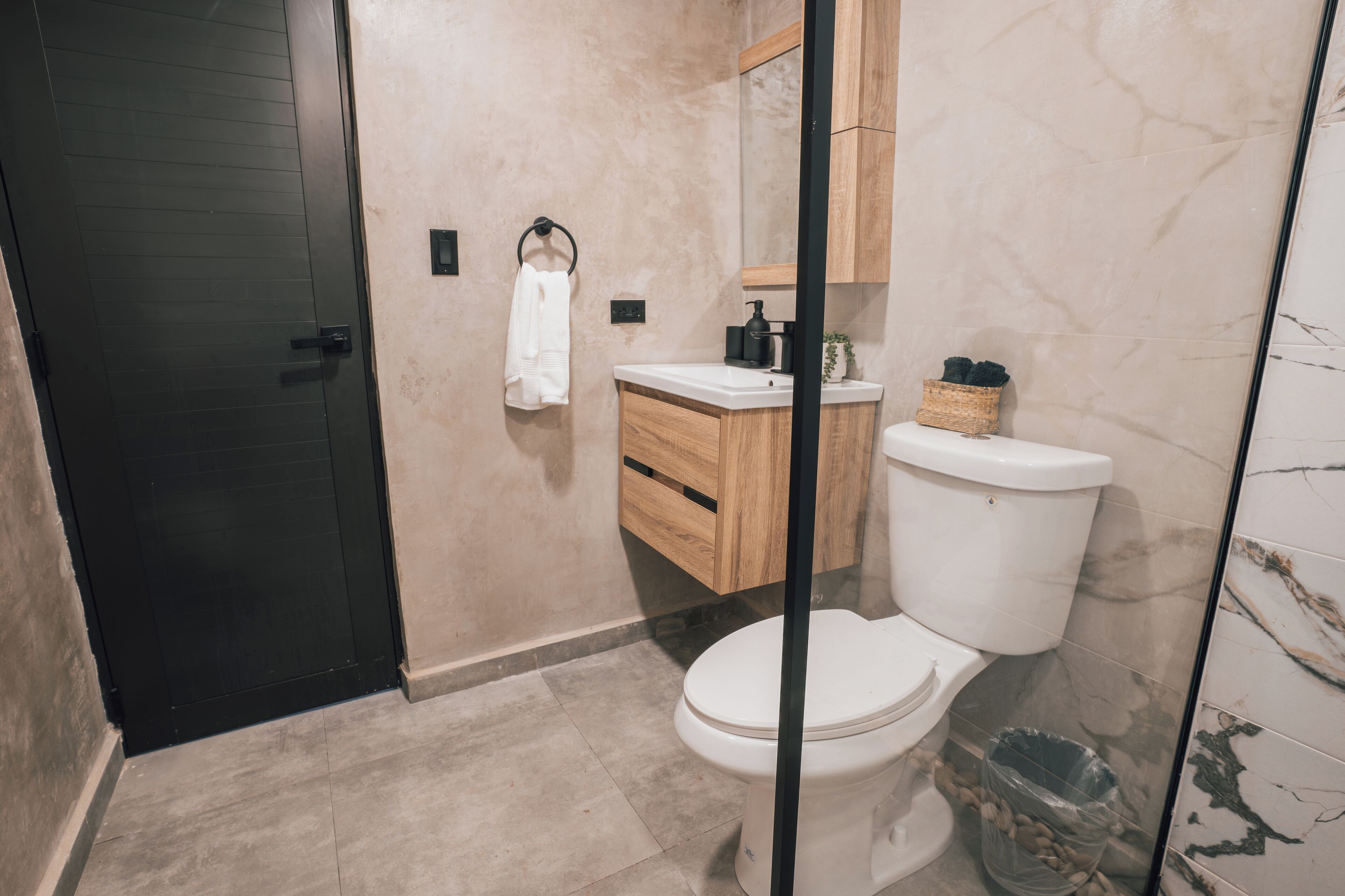 A modern bathroom with a toilet, vanity, and a large mirror.