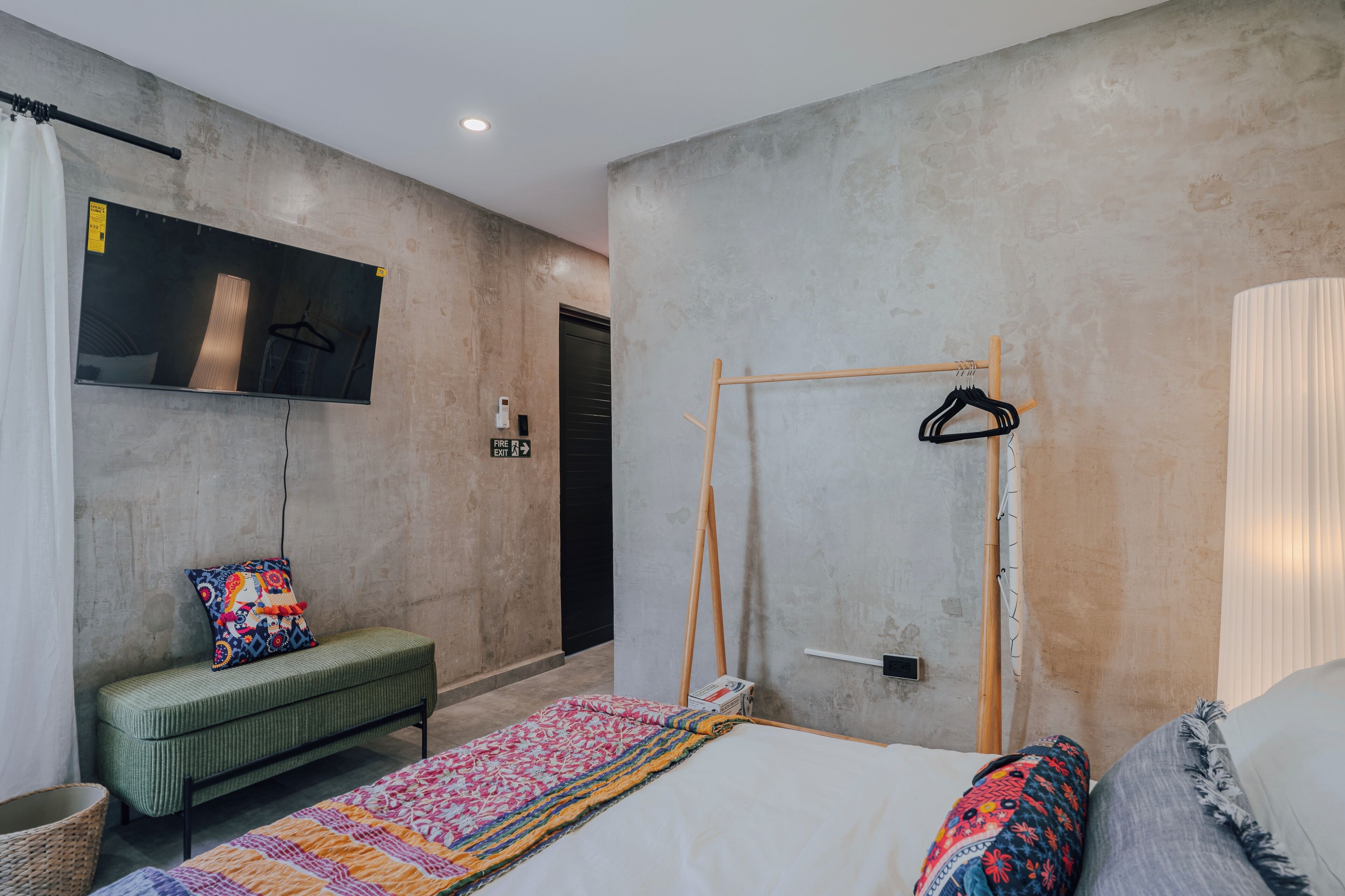 Un dormitorio con cama, un banco, televisor y armario.