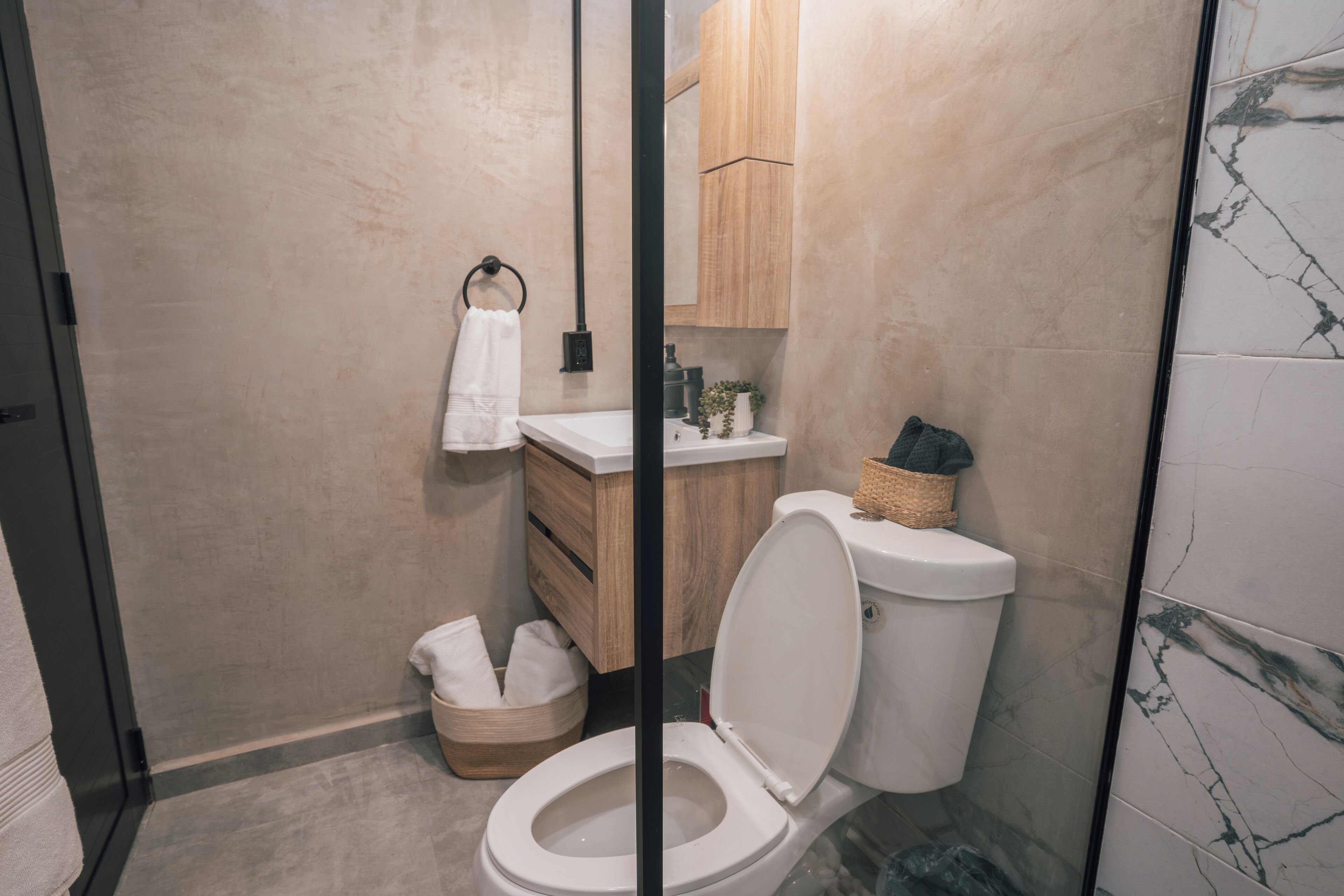 Ein modernes Badezimmer mit Toilette, Waschbecken und einem Holzkonsolentisch.