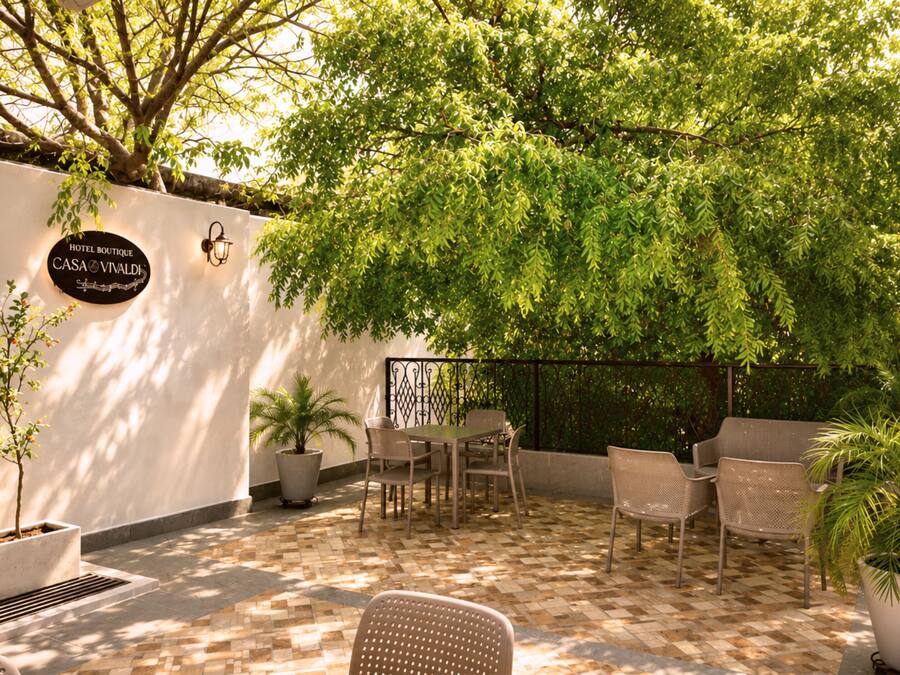 A patio area with a table and chairs, potted plants, and a wall-mounted sign.