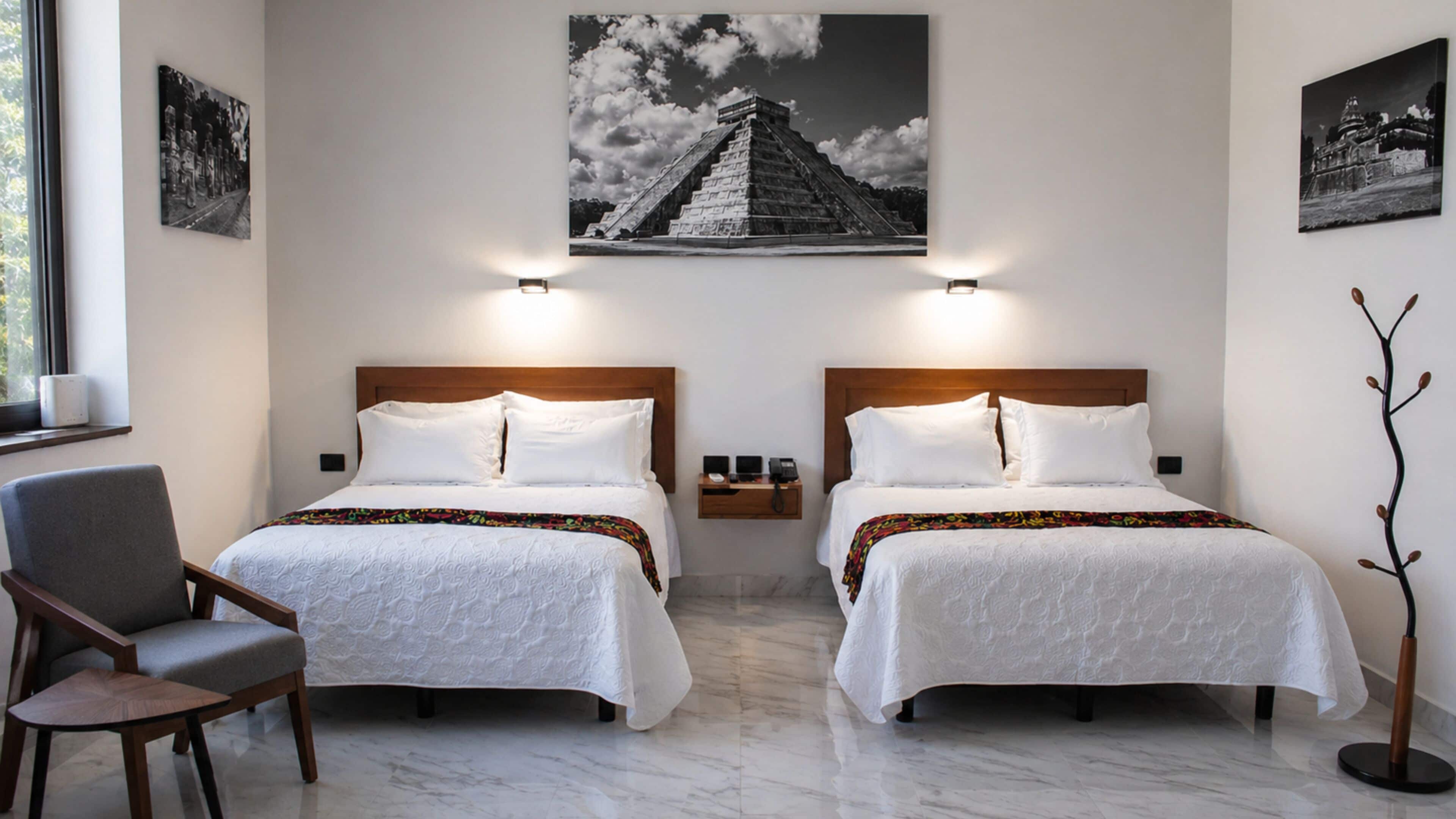 Een hotelkamer met twee bedden, een stoel, een nachtkastje en een wandlamp.