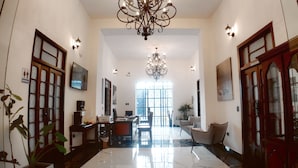 A spacious hallway with a chandelier, a dining area with a table and chairs, and a large window providing natural light.