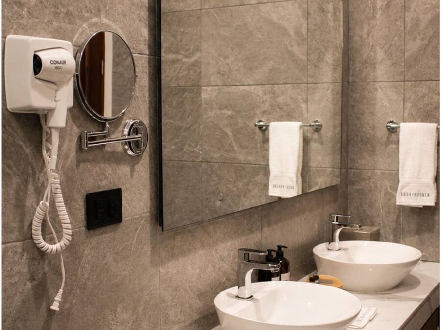 Un bany amb un lavabo doble, un assecador, un mirall i un penjador de tovalloles.