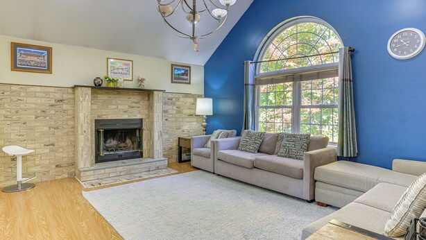 A living room with a fireplace, a sofa, a coffee table, and a large window with curtains. - Hike, Ski & Explore: Otisville Retreat w/ Yard! (Otisville)