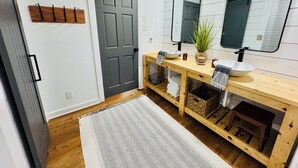 A bathroom with a wooden vanity, a large mirror, a sink, and a door. - Horton House SLEEPS 16, no pets or unapproved parties (Monroe)