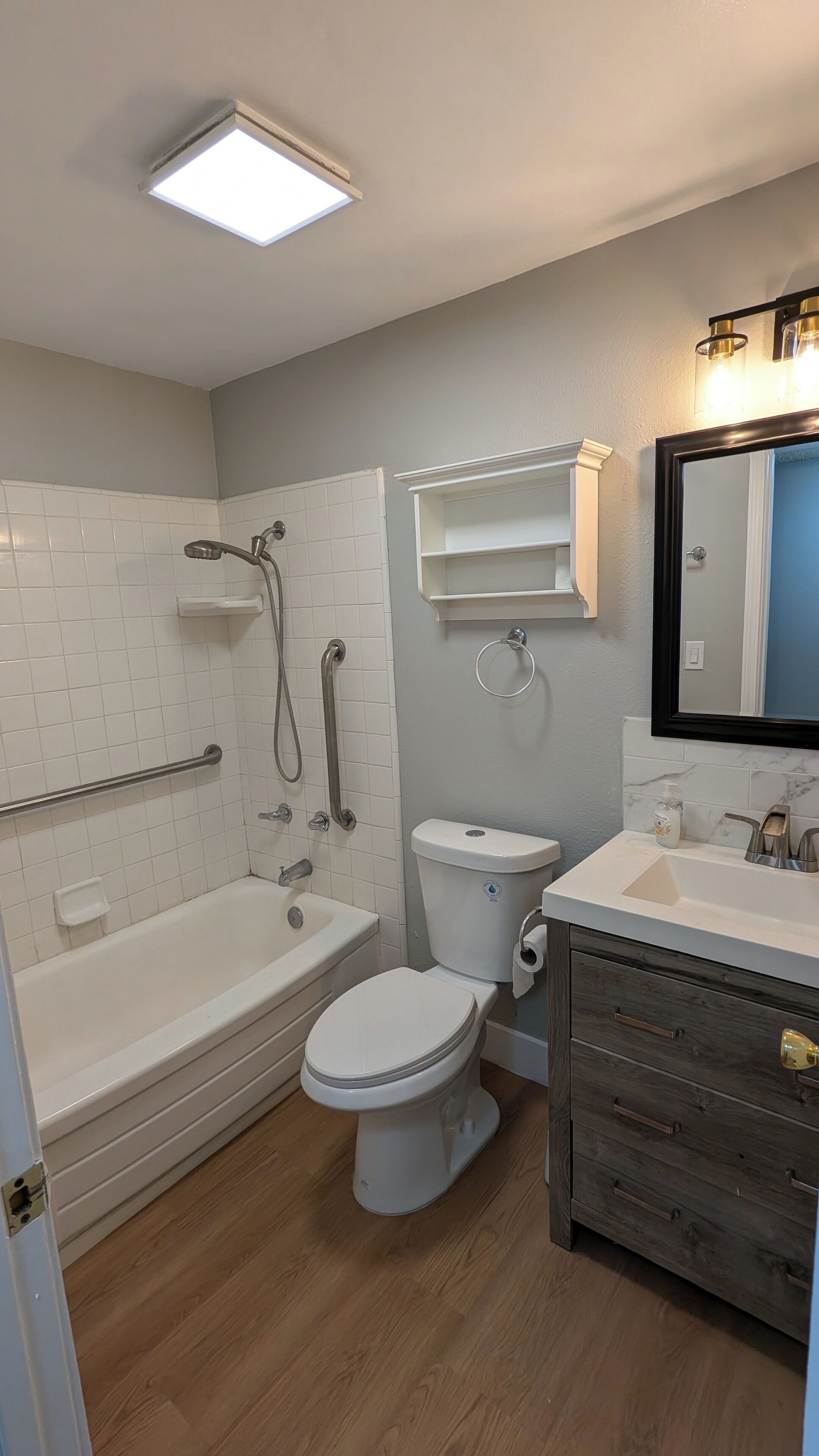 Un baño con bañera, inodoro y tocador con espejo.
