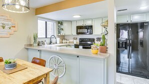 A kitchen with a central island, a dining table with chairs, and a refrigerator. - 3 Mi to Sabino Canyon: Condo w/ Resort Perks! (Tucson)