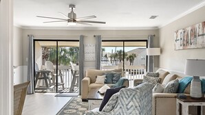 Amplia sala de estar con un ventanal grande, ventilador de techo y vistas al exterior.