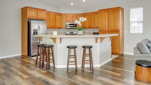 A modern kitchen with wooden cabinets, a stainless steel refrigerator, a built-in oven, and a central island with stools. - Quiet & Convenient! Santa Rosa Family Home w/ Yard (Santa Rosa)