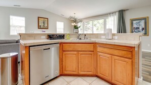 A modern kitchen with wooden cabinets, a dishwasher, and a countertop with various appliances. - Quiet & Convenient! Santa Rosa Family Home w/ Yard (Santa Rosa)