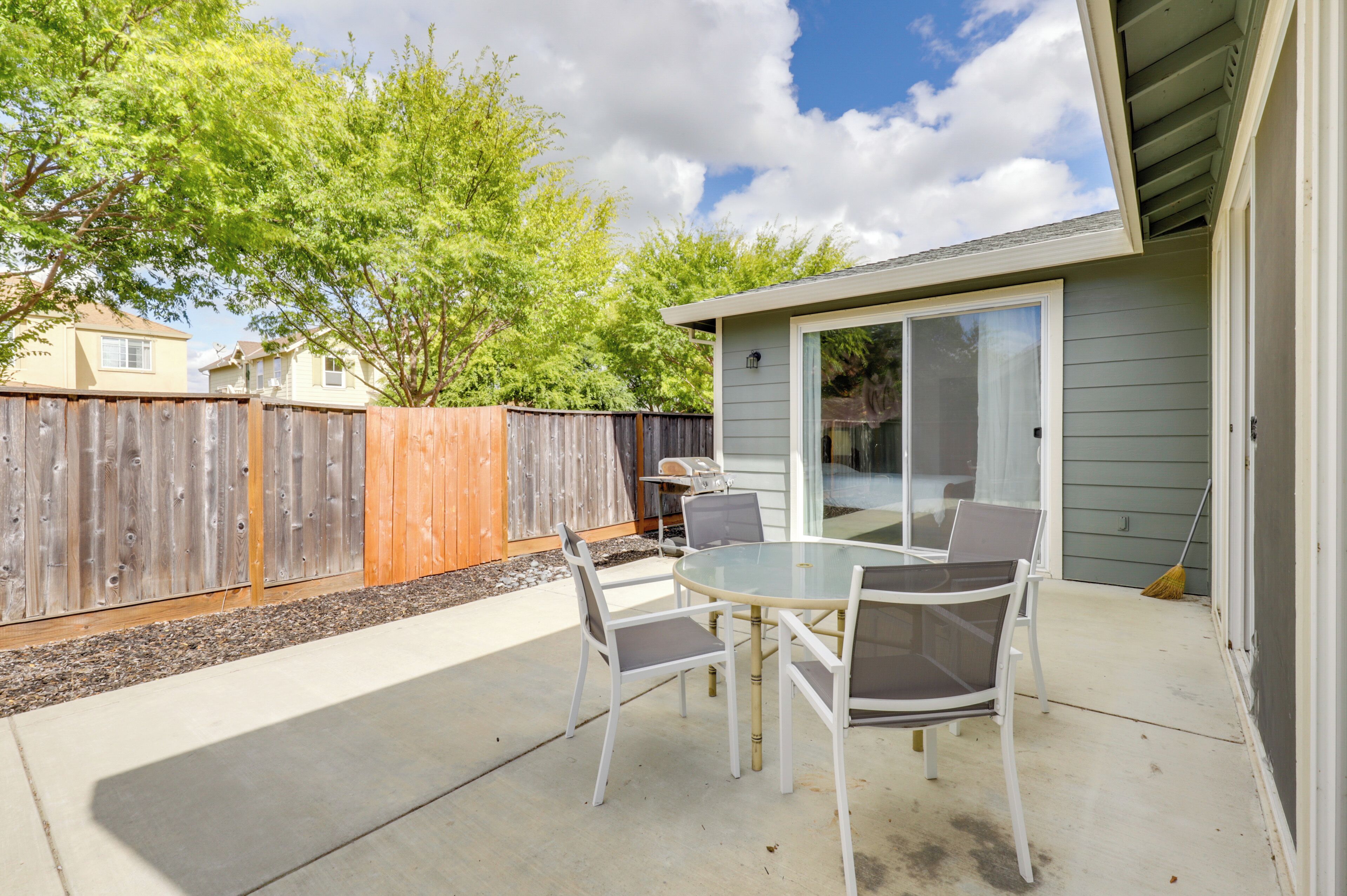A patio with a glass door, a wooden fence, and a table with chairs.