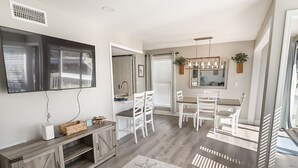 A modern kitchen with white cabinetry, a built-in oven, and a dining area with white chairs and a table. - Sandpiper Cove Unit 1027  1 Bedroom With FREE Beach Service (Destin)