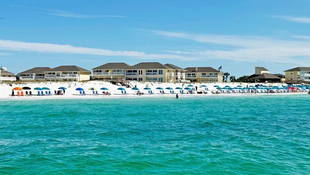 Ein Hotel direkt am Strand mit mehreren Gebäuden, einem Sandstrand und Sonnenschirmen.