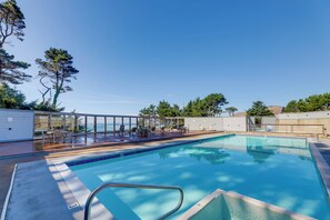 Une piscine rectangulaire à l’eau d’un bleu cristallin, entourée d’une terrasse avec des chaises longues et un espace clos par des parois de verre.