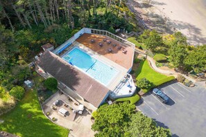 Vue aérienne d’une propriété dotée d’une piscine, d’un espace de détente extérieur et d’un parking.