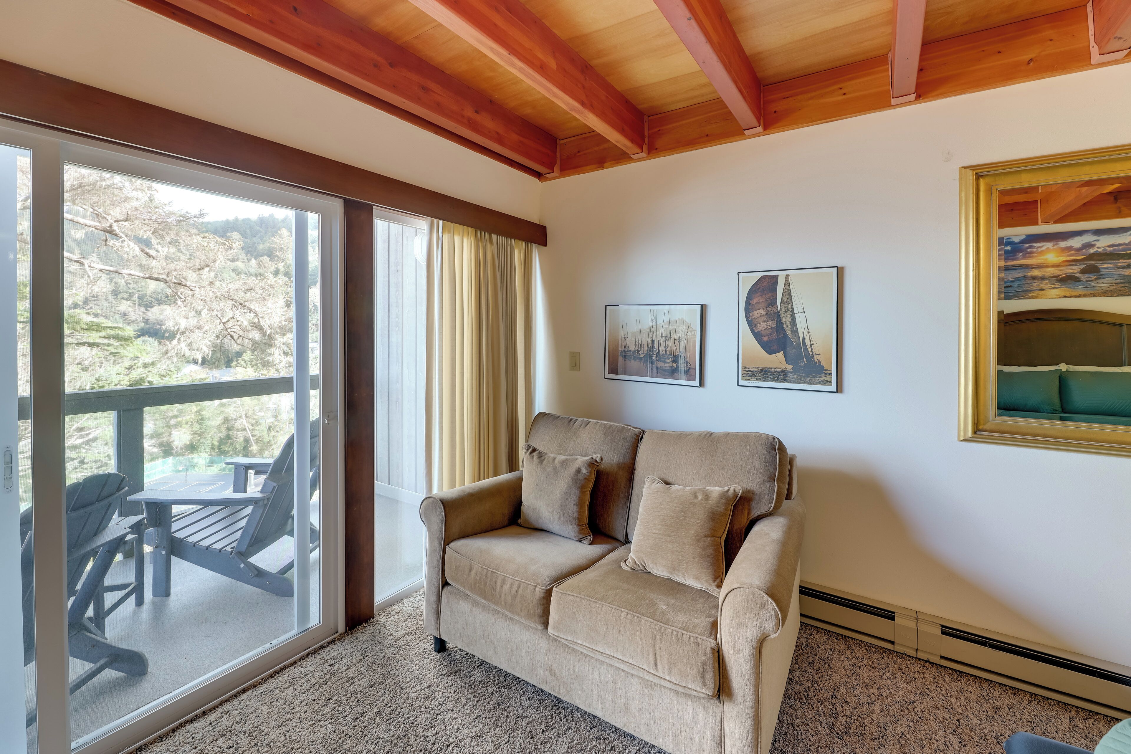 Un accogliente soggiorno con un divano beige, un soffitto in legno e un'ampia finestra che si affaccia su un patio.