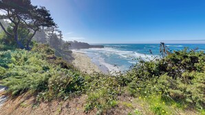 A coastal landscape with a beach, ocean waves, and dense vegetation. - Steps to Otter Crest Beach: Studio w/ Resort Perks (Newport)