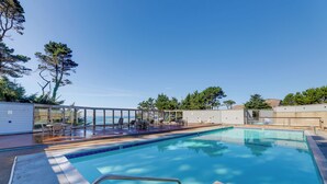 A rectangular swimming pool with clear blue water, surrounded by a deck with lounge chairs and a glass-enclosed area. - Steps to Otter Crest Beach: Studio w/ Resort Perks (Newport)
