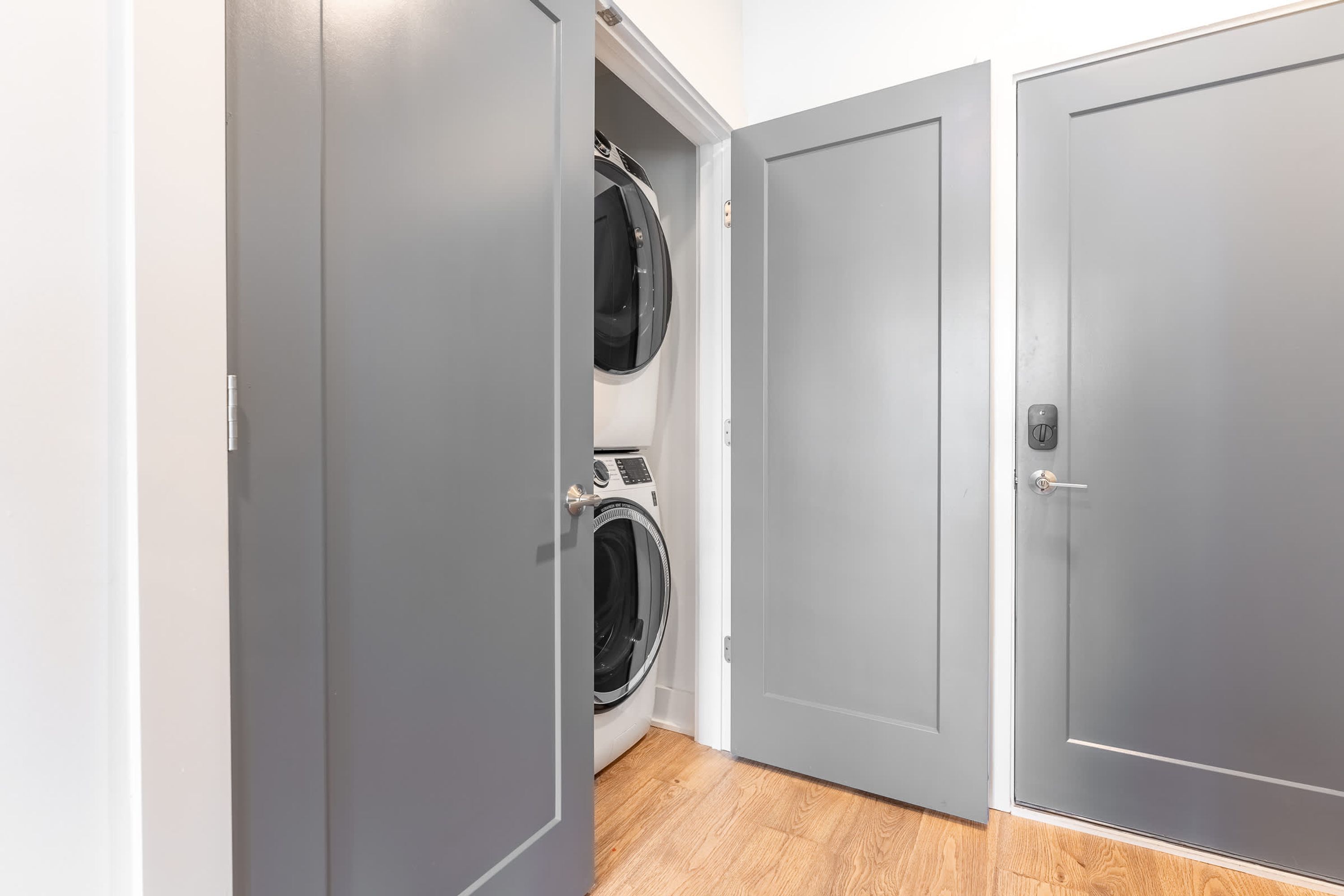 A laundry room with two washing machines and grey doors.