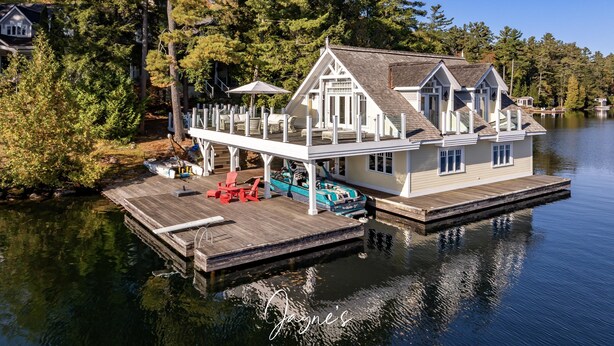 A lakeside house with a dock, a covered deck, and a boat.