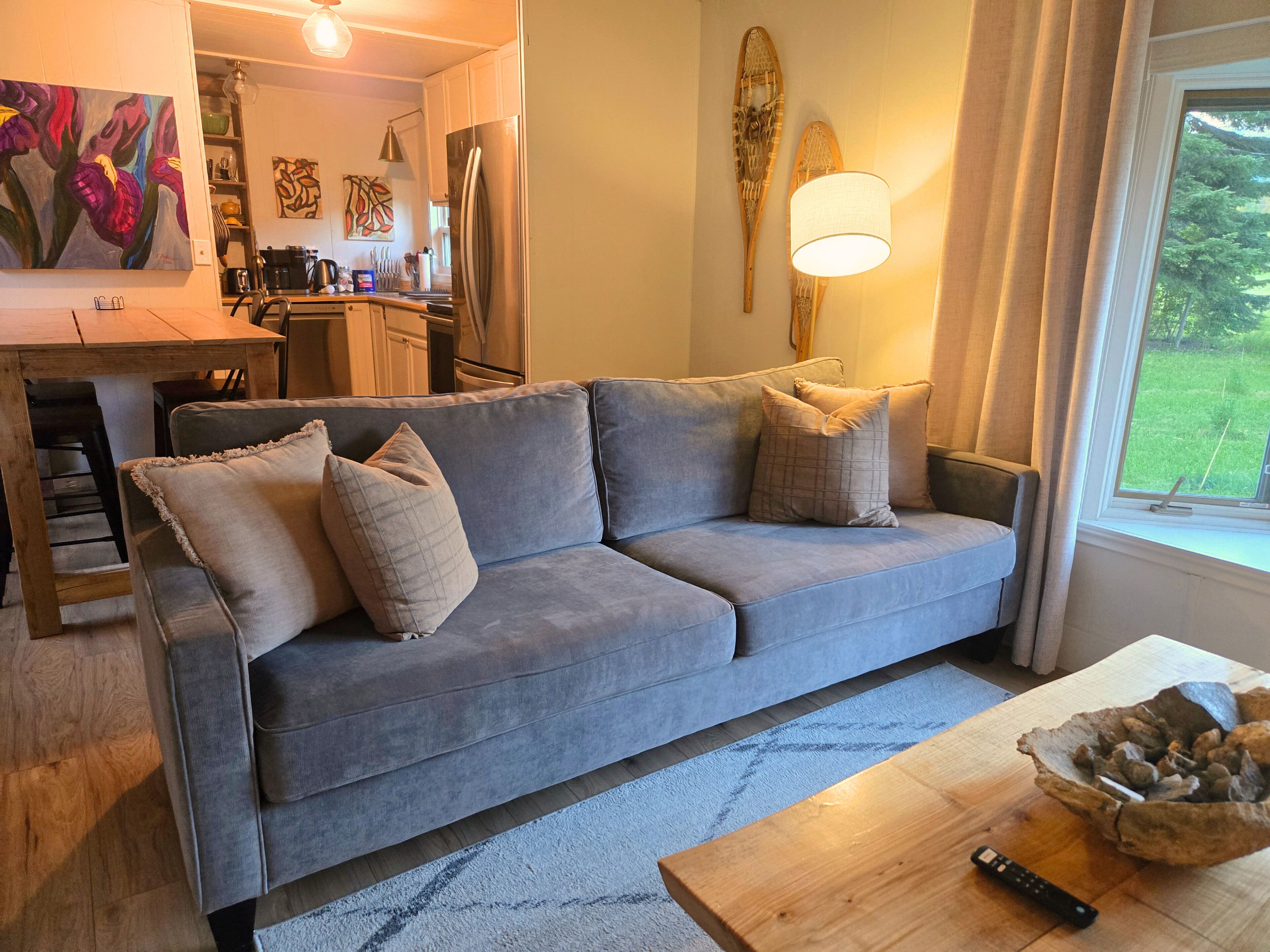 A living room with a grey sofa, a wooden coffee table, and a remote control.