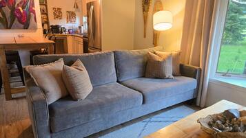 A living room with a grey sofa, a wooden coffee table, and a remote control.