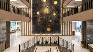 Eine großzügige Lobby mit einer zeitgenössischen Kunstinstallation, einem Marmorboden und einer Treppe mit schwarzen Geländern.