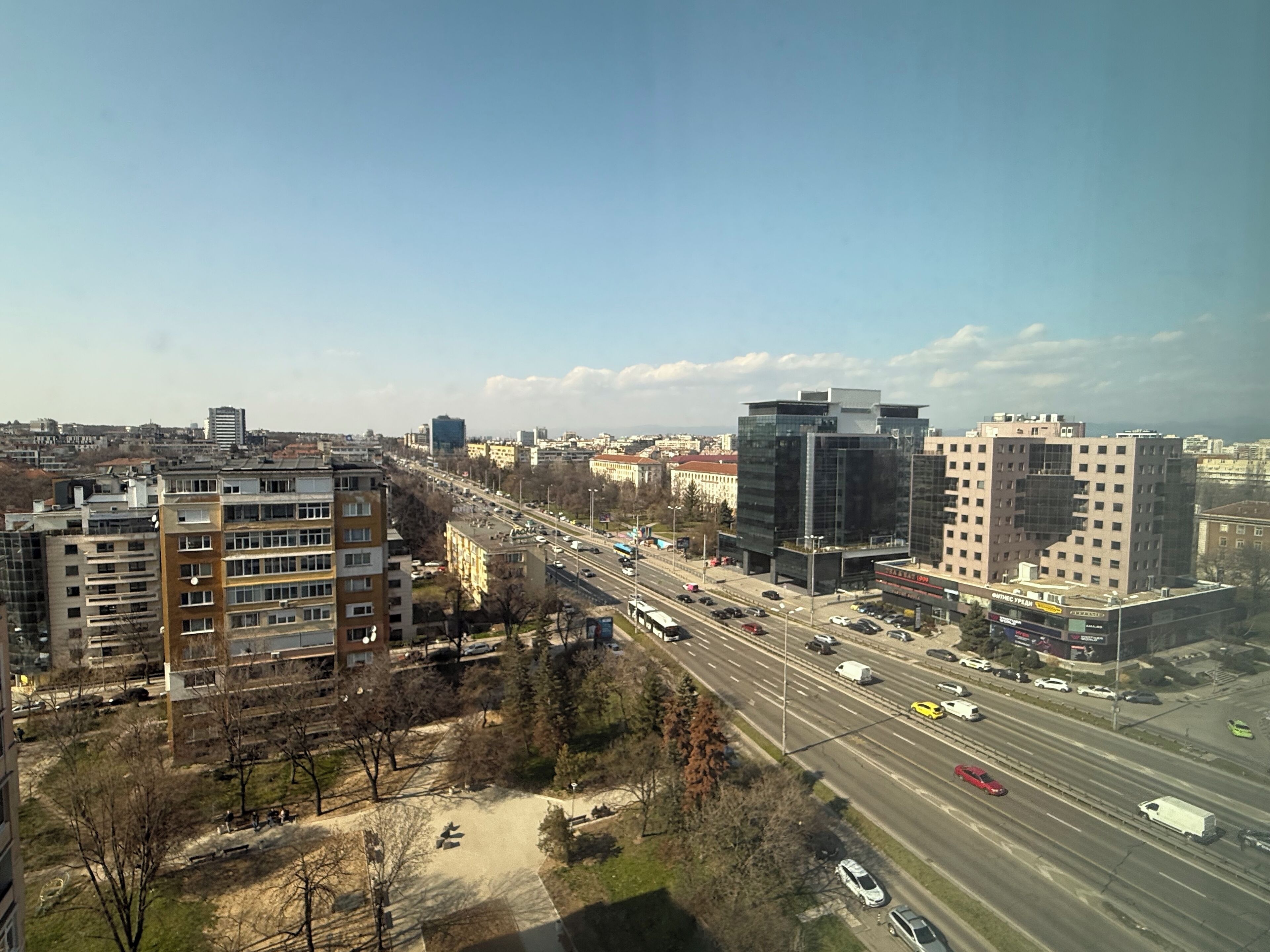 A cityscape with modern buildings, a highway, and a clear sky.