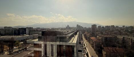 Un edificio moderno con fachada de vidrio, rodeado de construcciones urbanas y un cielo despejado.