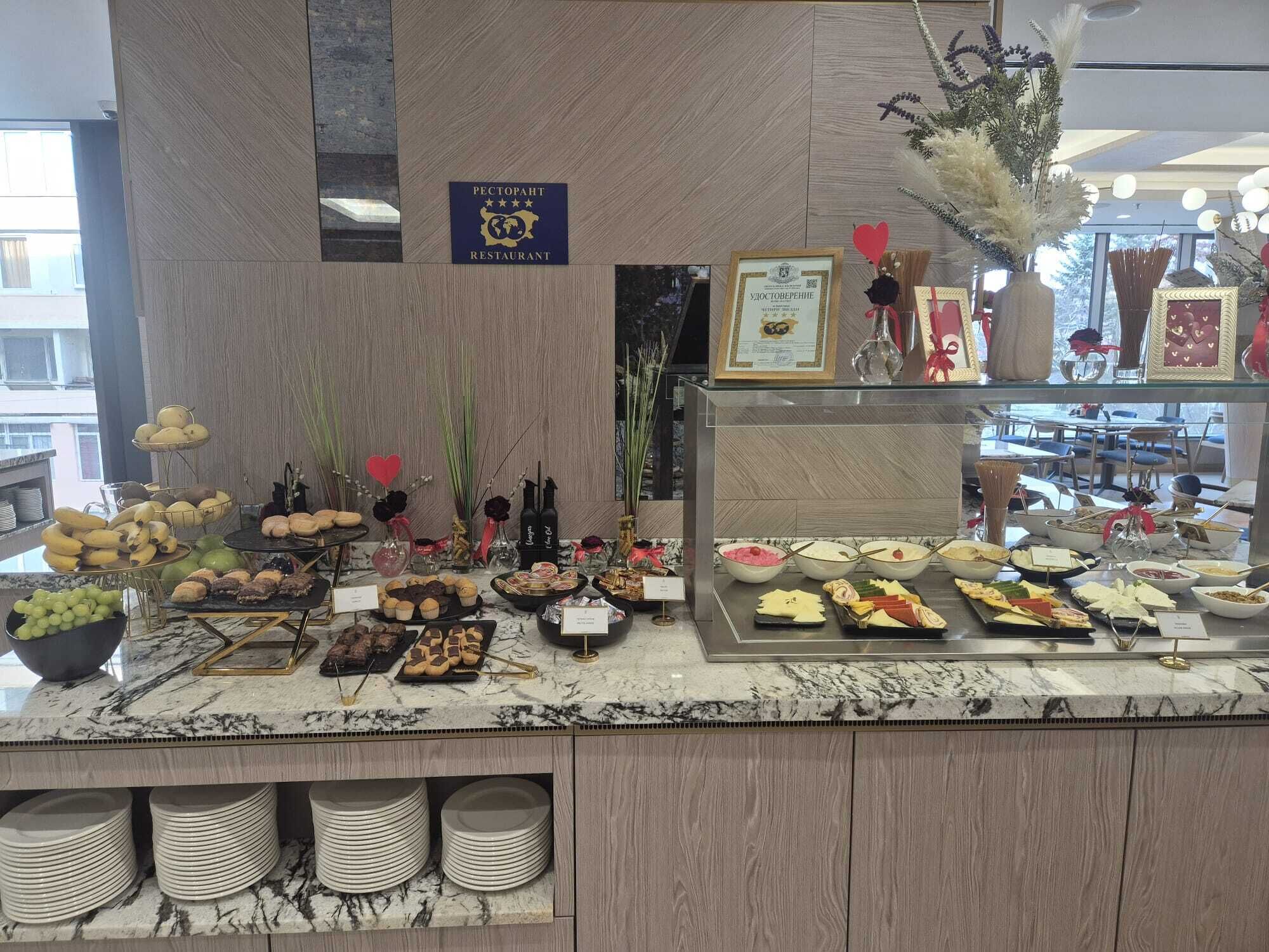 A buffet counter with various food items, a sign indicating a restaurant, and a certificate on display.