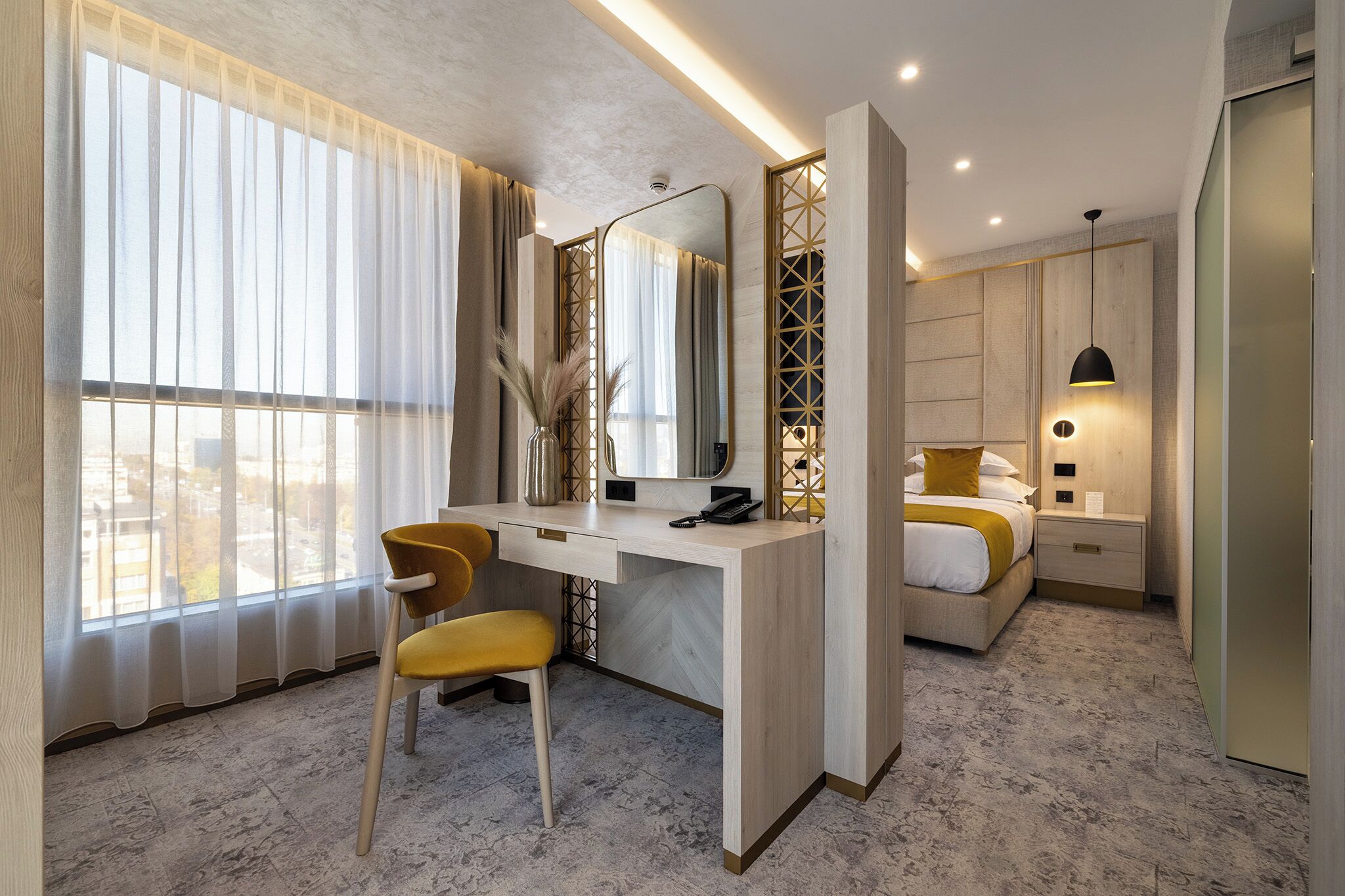 Une chambre d’hôtel moderne équipée d’un grand bureau, d’une chaise, d’un lit et d’une table de chevet.