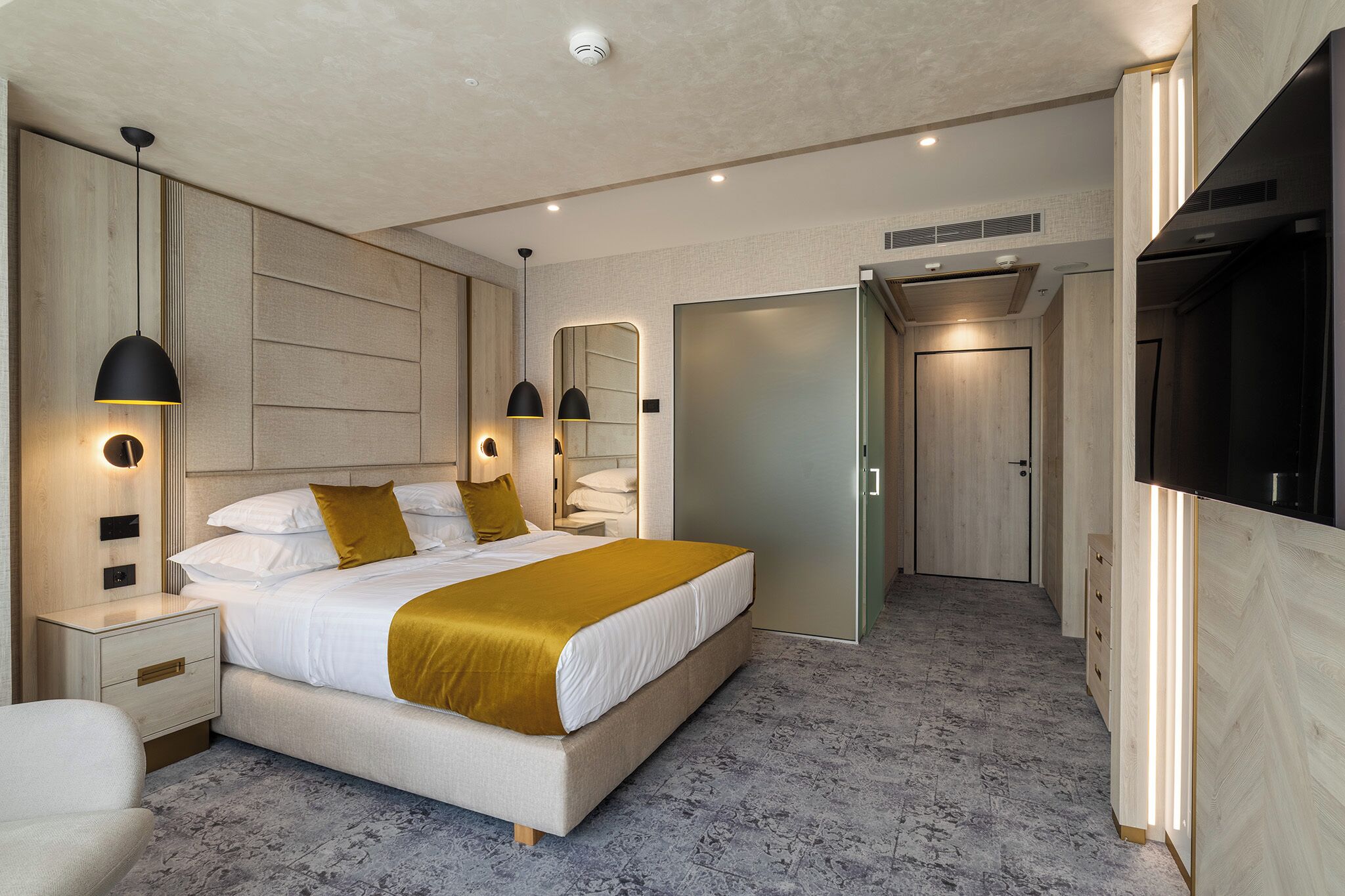 Un dormitorio moderno con una cama grande, mesitas de noche, un armario y un televisor.