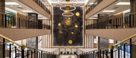 A modern interior with a central art installation, multiple floors, and a prominent staircase.