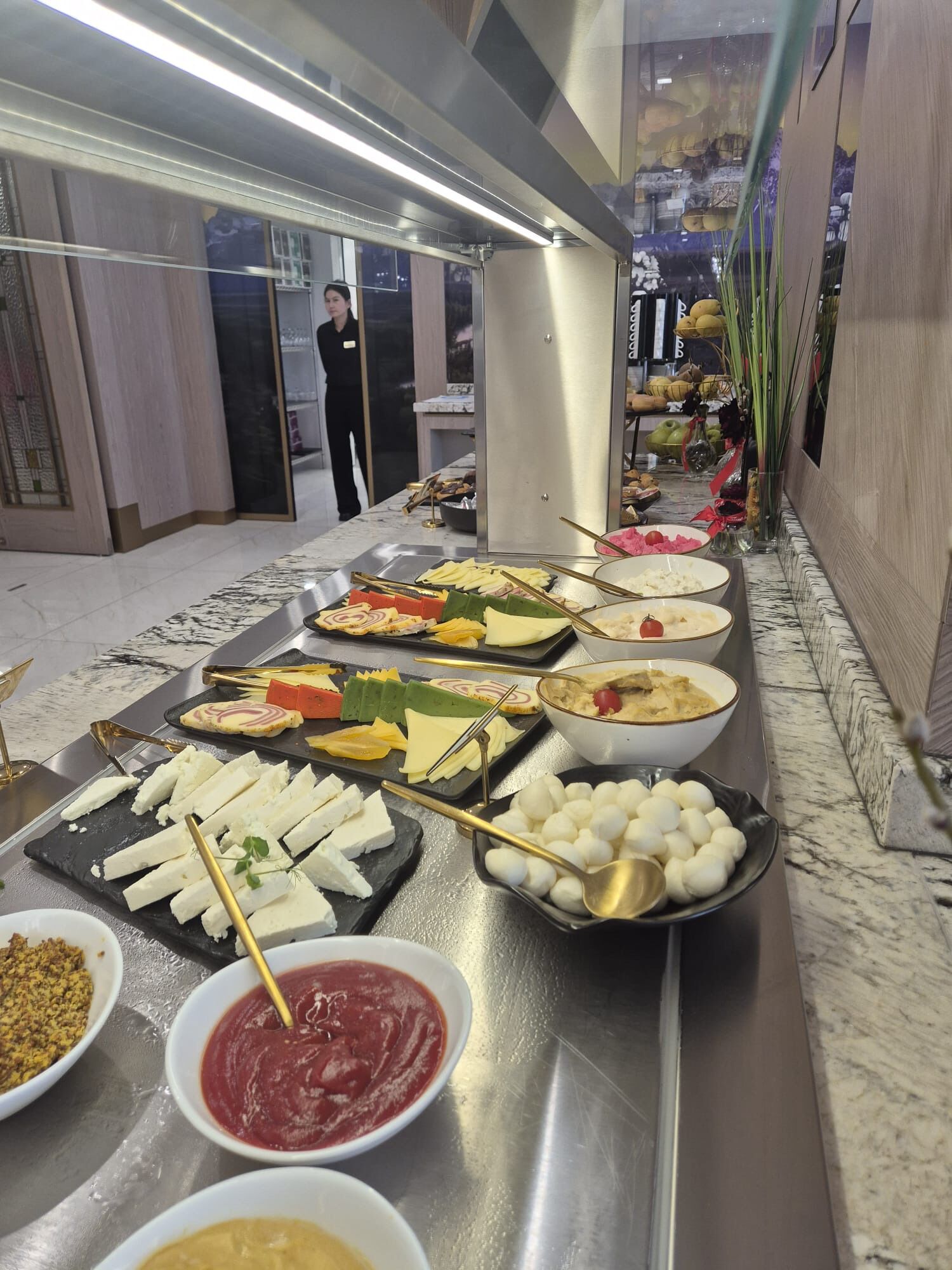 A buffet with various cheeses, fruits, and dips.