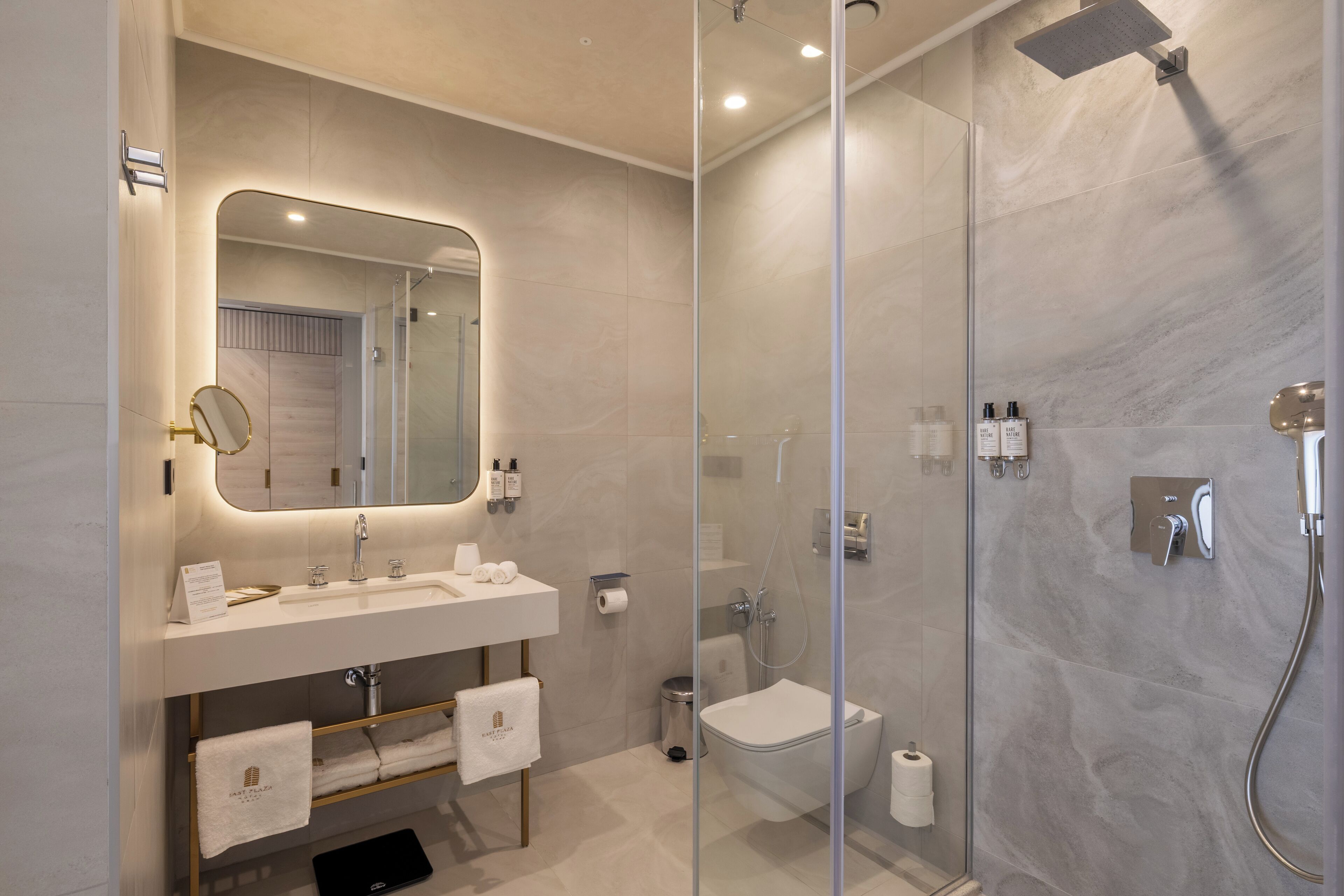 Un baño moderno con cabina de ducha de vidrio, tocador con espejo y un inodoro.