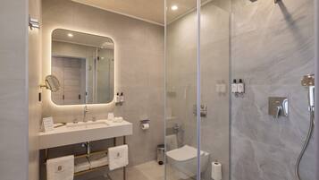Un baño moderno con cabina de ducha de vidrio, tocador con espejo y un inodoro.