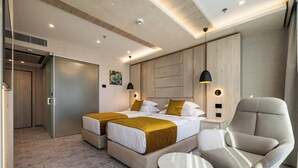 Ein Hotelzimmer mit einem Bett, zwei Nachttischen, einem Sessel und einem kleinen runden Tisch.